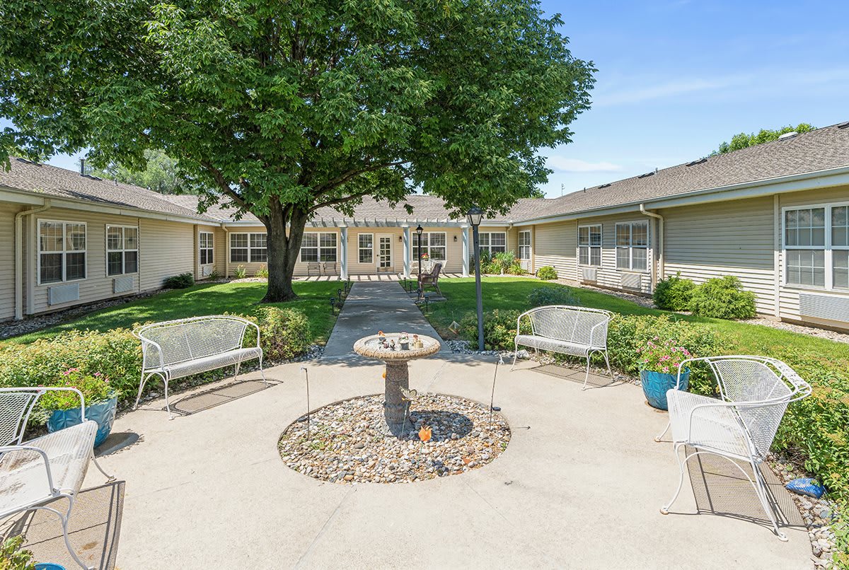A peaceful courtyard with benches, a central fountain, and lush greenery.