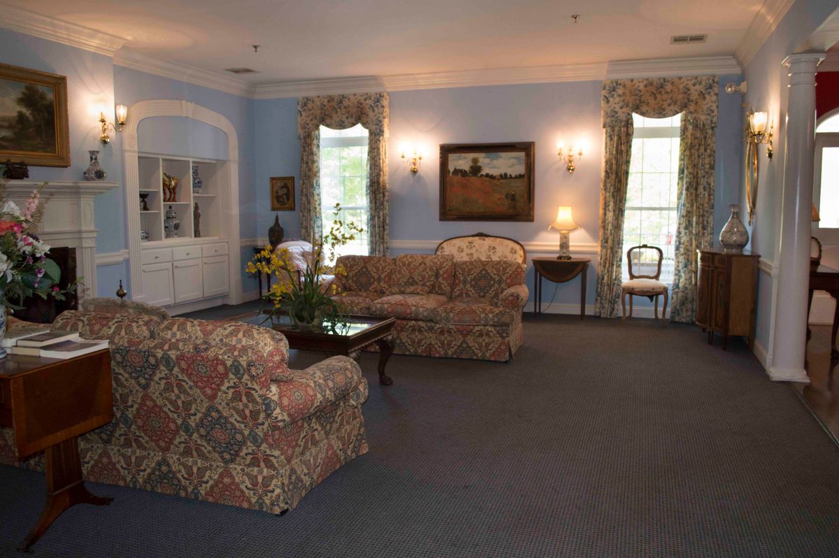 A traditionally decorated living room with floral-patterned sofas, a carpet, and classic furnishings.