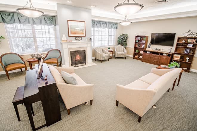 A cozy and well-lit living room with a fireplace, sofas, armchairs, and a television.