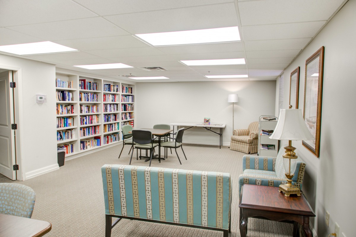 A quiet library space with bookshelves, seating, and tables for study or reading.