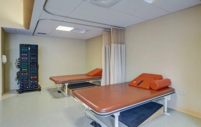A clinic treatment room with two medical beds and privacy curtains.