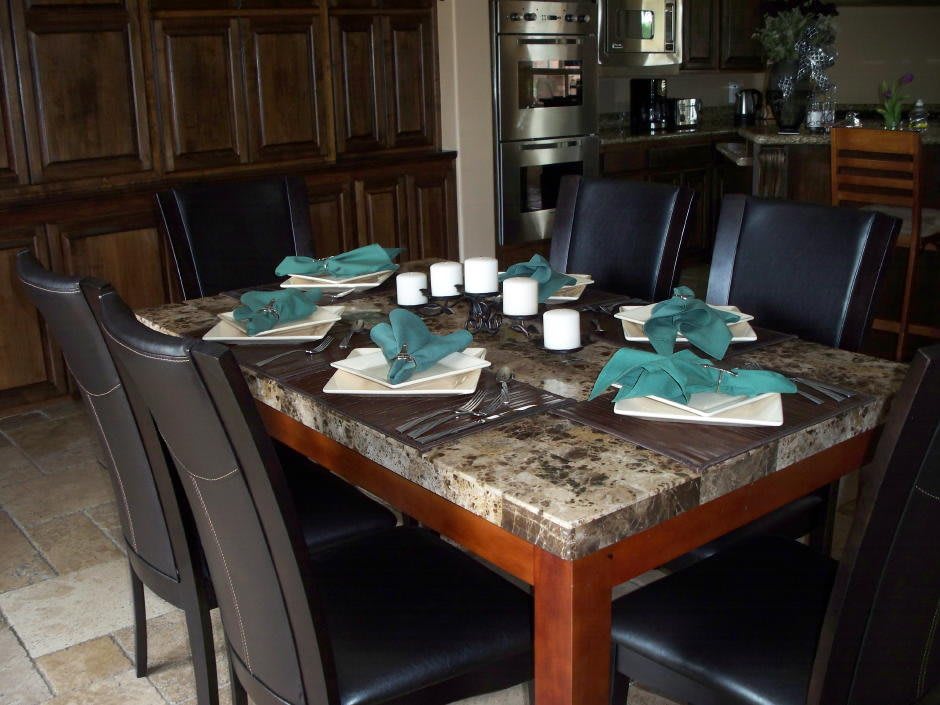 A well-set dining table with teal napkins and black chairs.