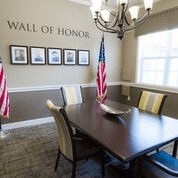 A conference room with a 'Wall of Honor' display, featuring photographs and two American flags.