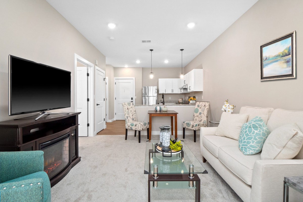 Modern open concept living room and kitchen with stylish furniture and bright lighting.