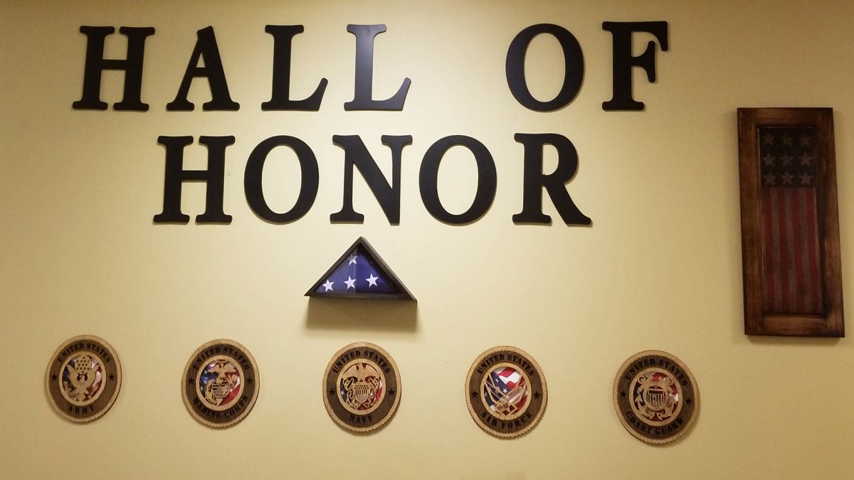 A display in the Hall of Honor featuring a folded American flag and military emblems.