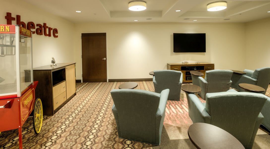 A cozy lounge area with chairs, a table, and a wall-mounted television.