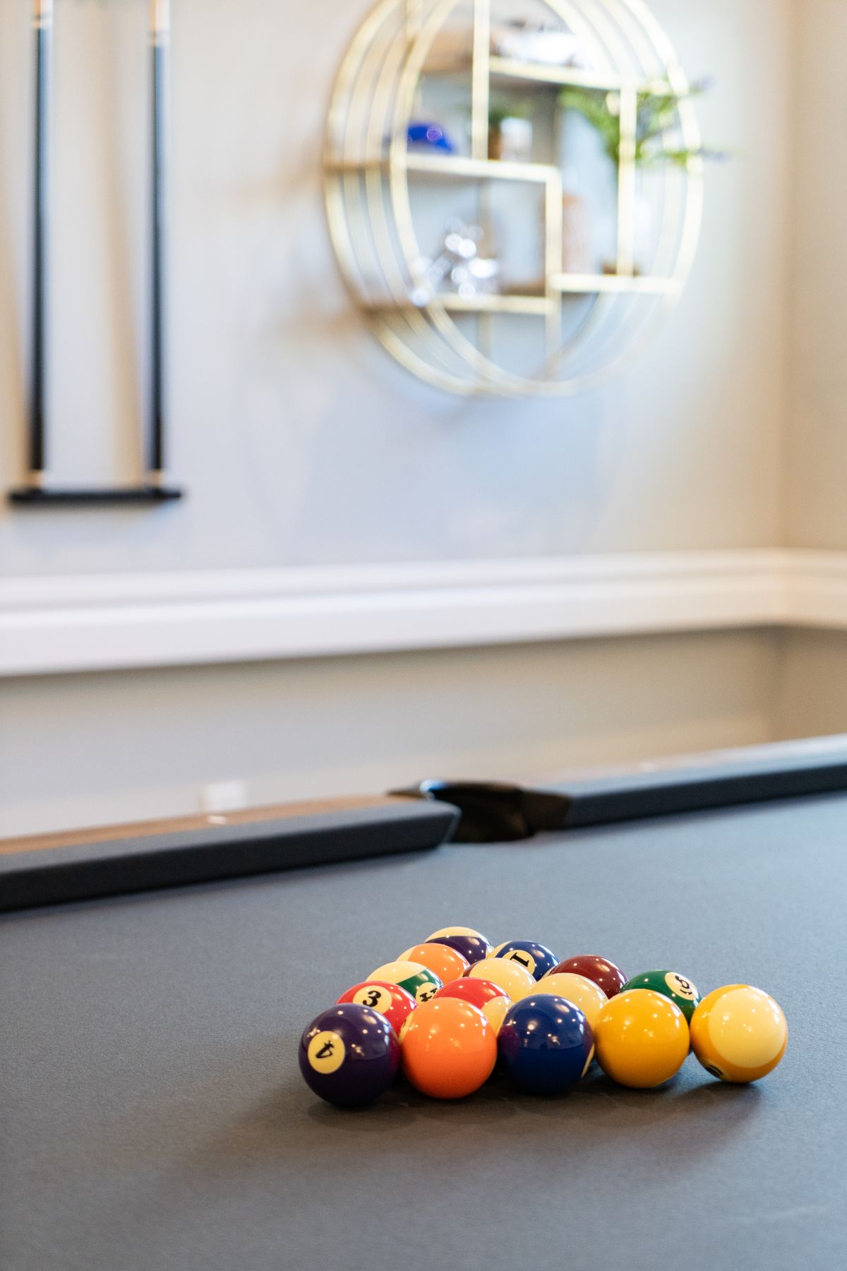 A neatly racked set of billiard balls on a pool table in a stylish game room.