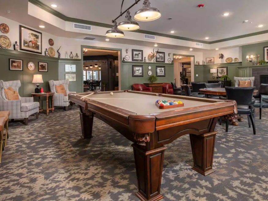 A cozy billiard room featuring a classic pool table surrounded by vintage decor and comfortable seating.