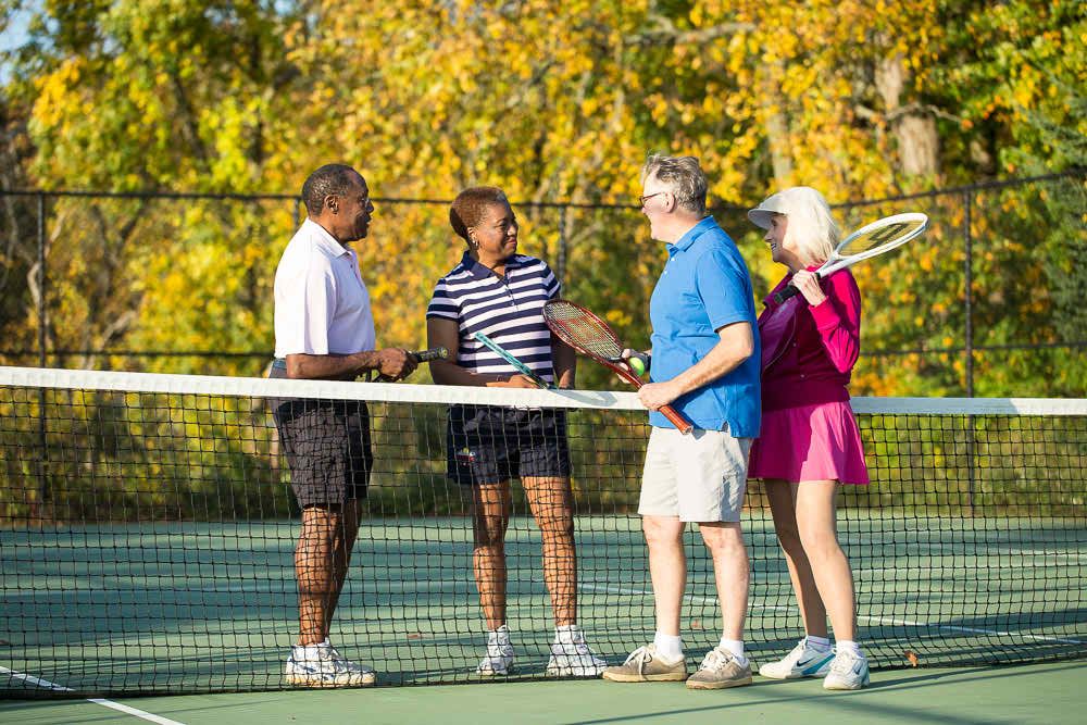 A group of friends enjoying a game of tennis together outdoors.