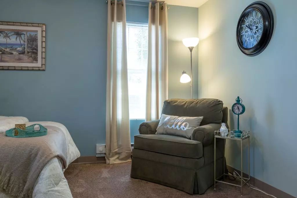 A cozy reading nook featuring an armchair and a floor lamp by the window.