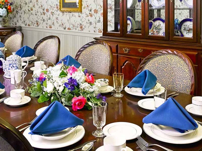A formal dining table set with blue napkins, floral centerpiece, and elegant dinnerware.