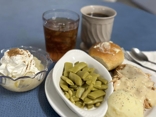 A comforting home-cooked meal featuring green beans, a roll, and dessert accompanied by tea and coffee.