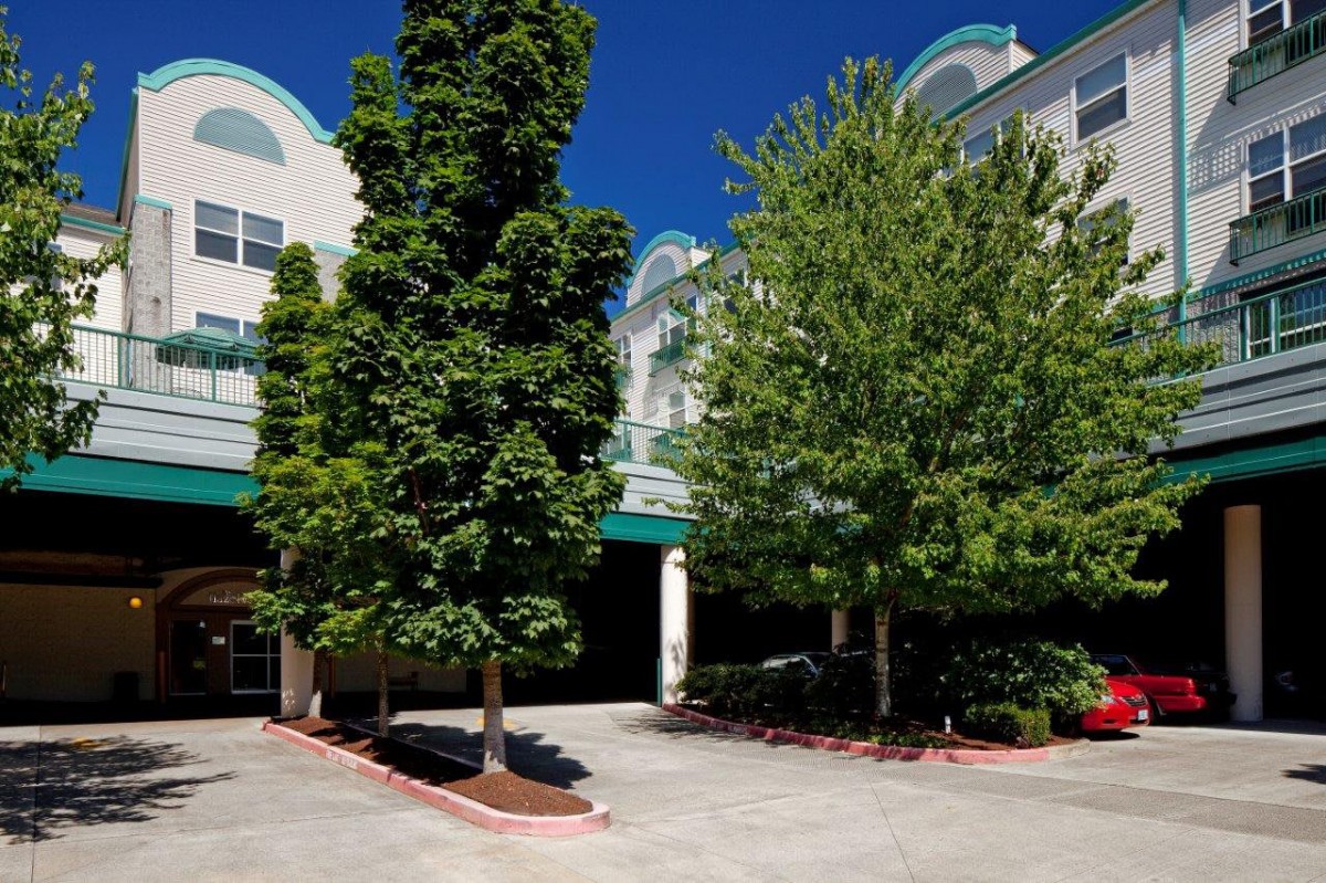 The image shows a building with trees in the foreground on a clear day.