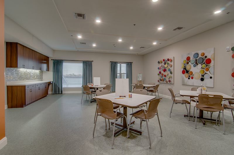 A modern and spacious dining area with tables and chairs, featuring contemporary artwork and soft lighting.