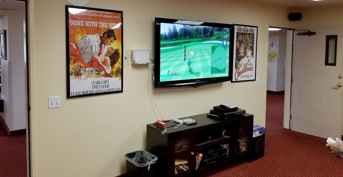 A living room with a TV displaying a golf video game, surrounded by classic movie posters.