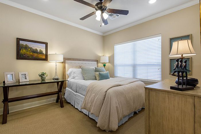 A cozy bedroom interior featuring a neatly made bed, soft lighting, and a ceiling fan.