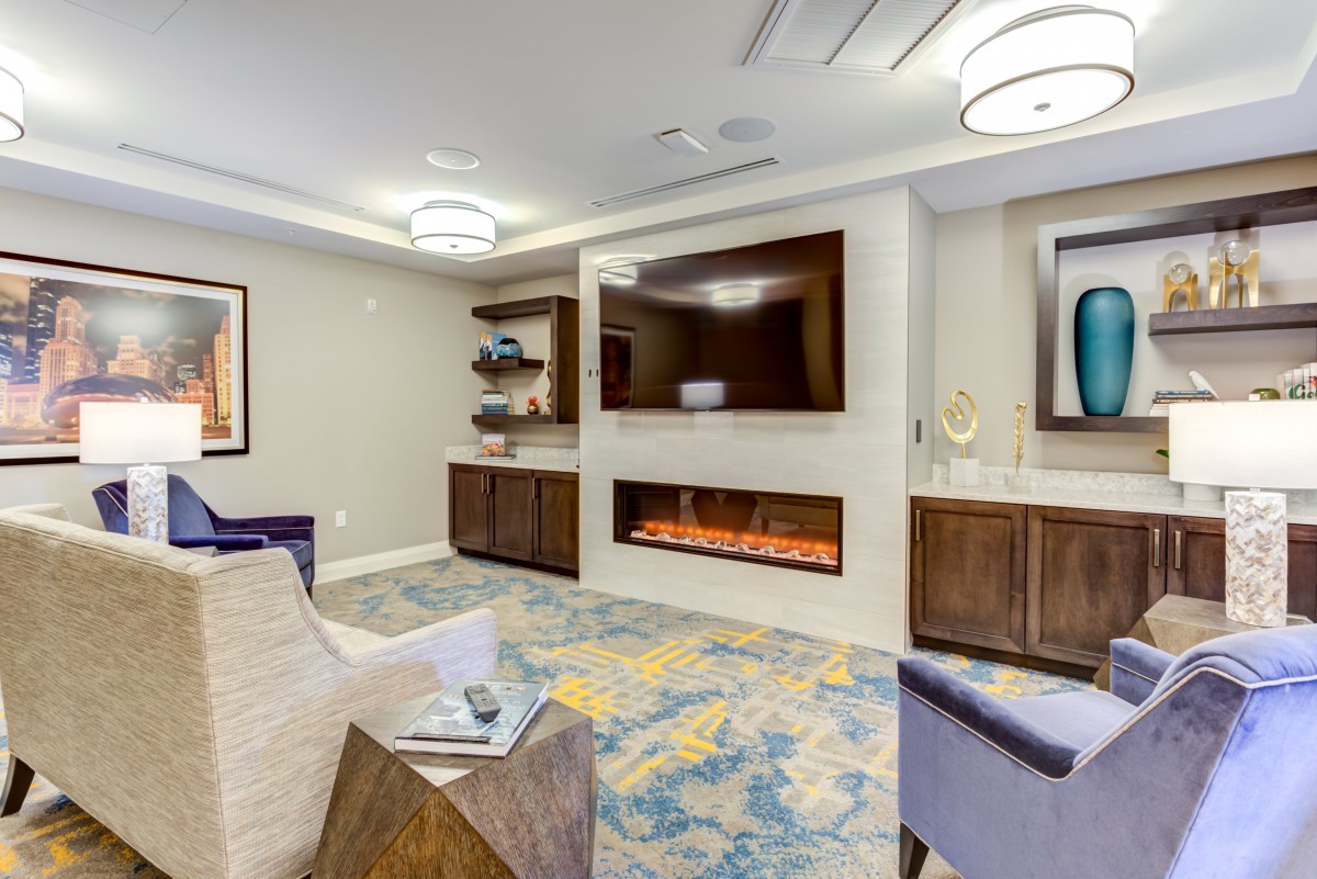 A modern living room with a fireplace and television, featuring comfortable seating and stylish decor.