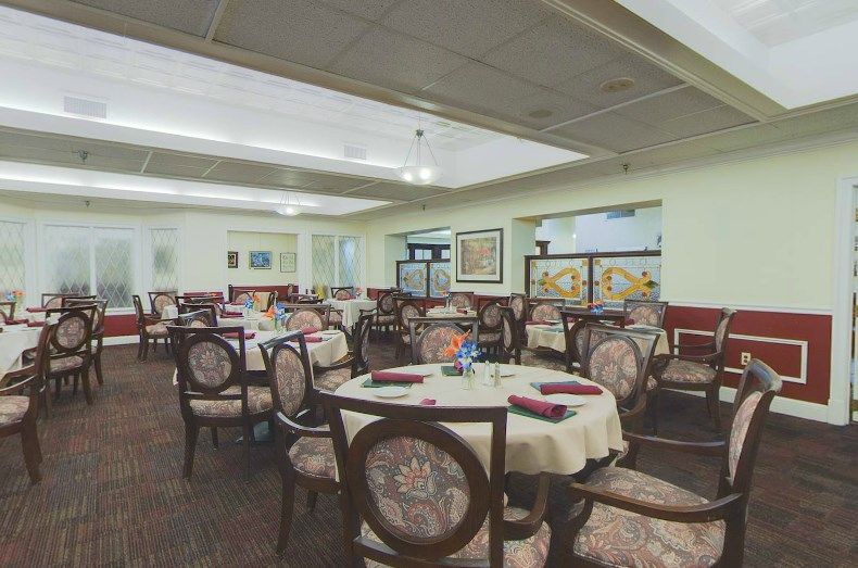 An elegant restaurant dining area with neatly arranged tables and chairs, each adorned with tablecloths.