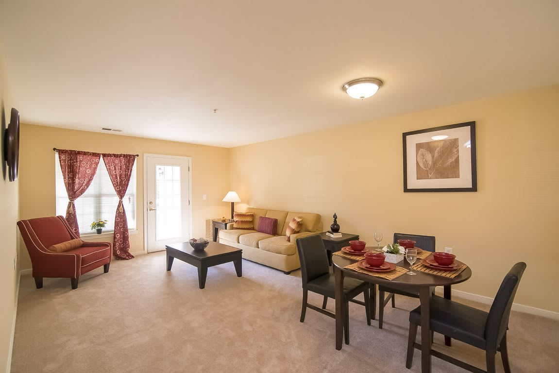 A cozy living room with a dining area, featuring a sofa, coffee table, and dining table with chairs.