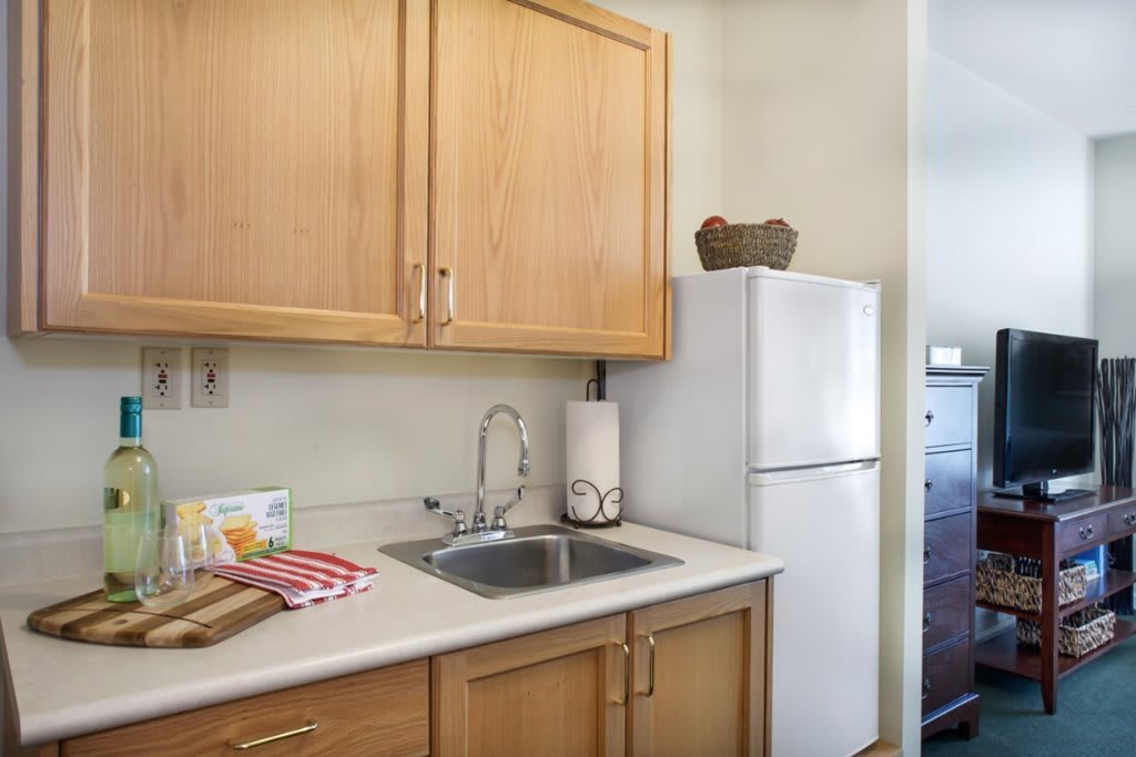 A small kitchen area with wooden cabinets, a countertop with a sink, and a refrigerator.