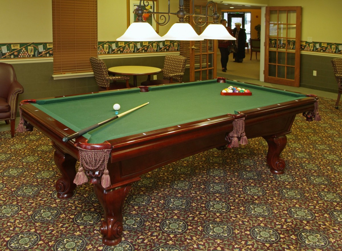 A well-lit game room featuring a classic pool table with green felt.