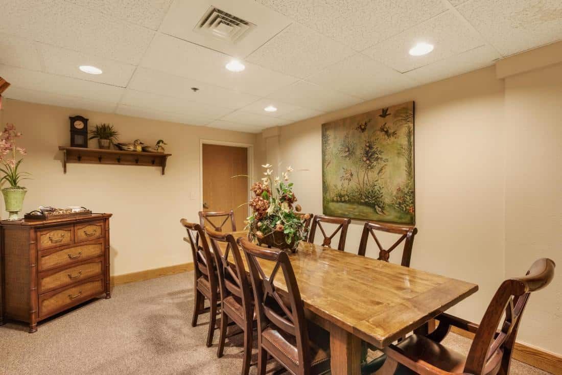 A cozy dining room with a long wooden table surrounded by chairs and decorated with artwork and floral arrangements.