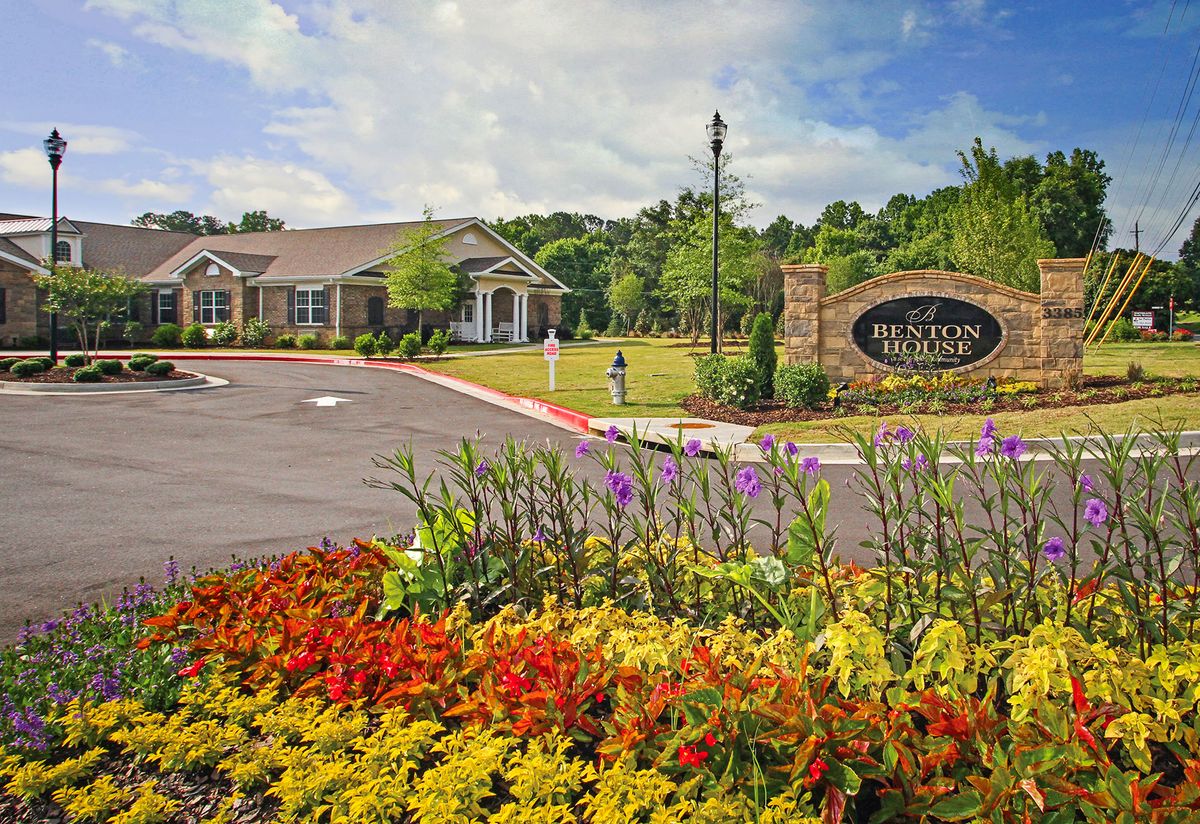 A beautifully landscaped garden with vibrant flowers in front of a building and a welcoming sign.