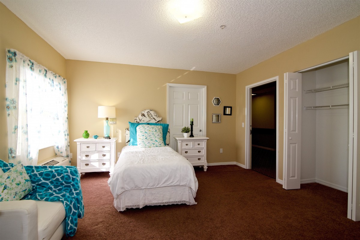 A cozy bedroom with a single bed, nightstands, and warm lighting.
