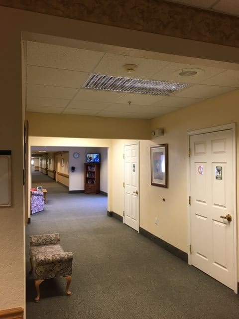 A well-lit hallway with multiple doors and a carpeted floor.