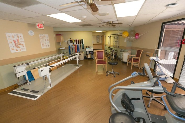 A rehabilitation room equipped with parallel bars and various exercise equipment for therapy.