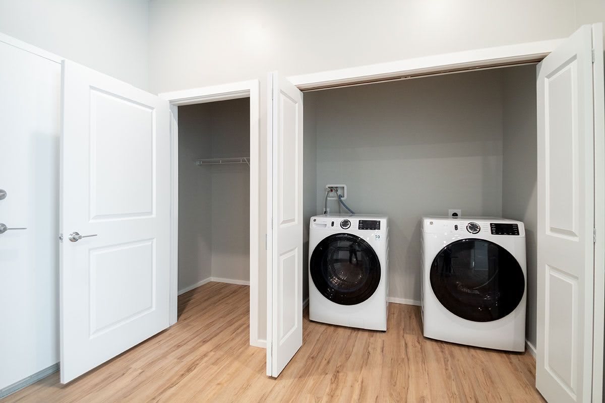 A modern laundry room with a washer and dryer set against a wooden floor.