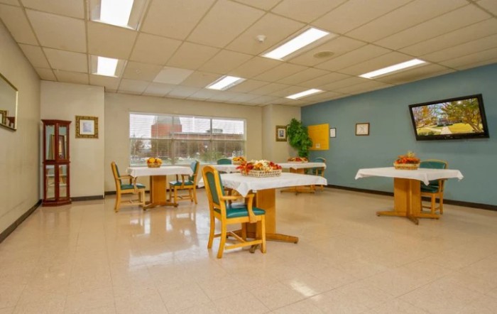 An empty dining room with neatly arranged tables and chairs, illuminated by ceiling lights.