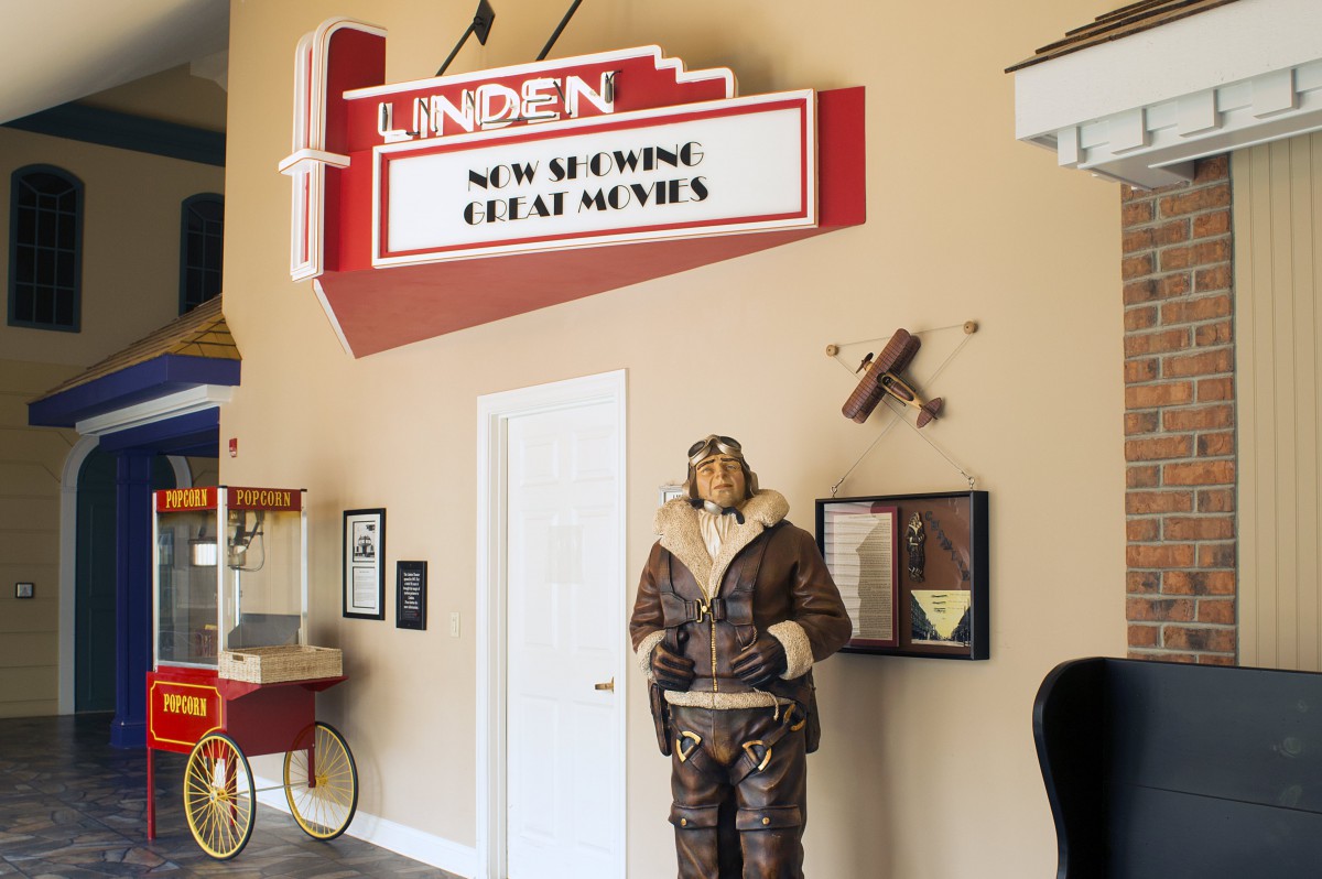 A vintage movie theater theme with a classic marquee sign, an aviator mannequin, and a popcorn machine.