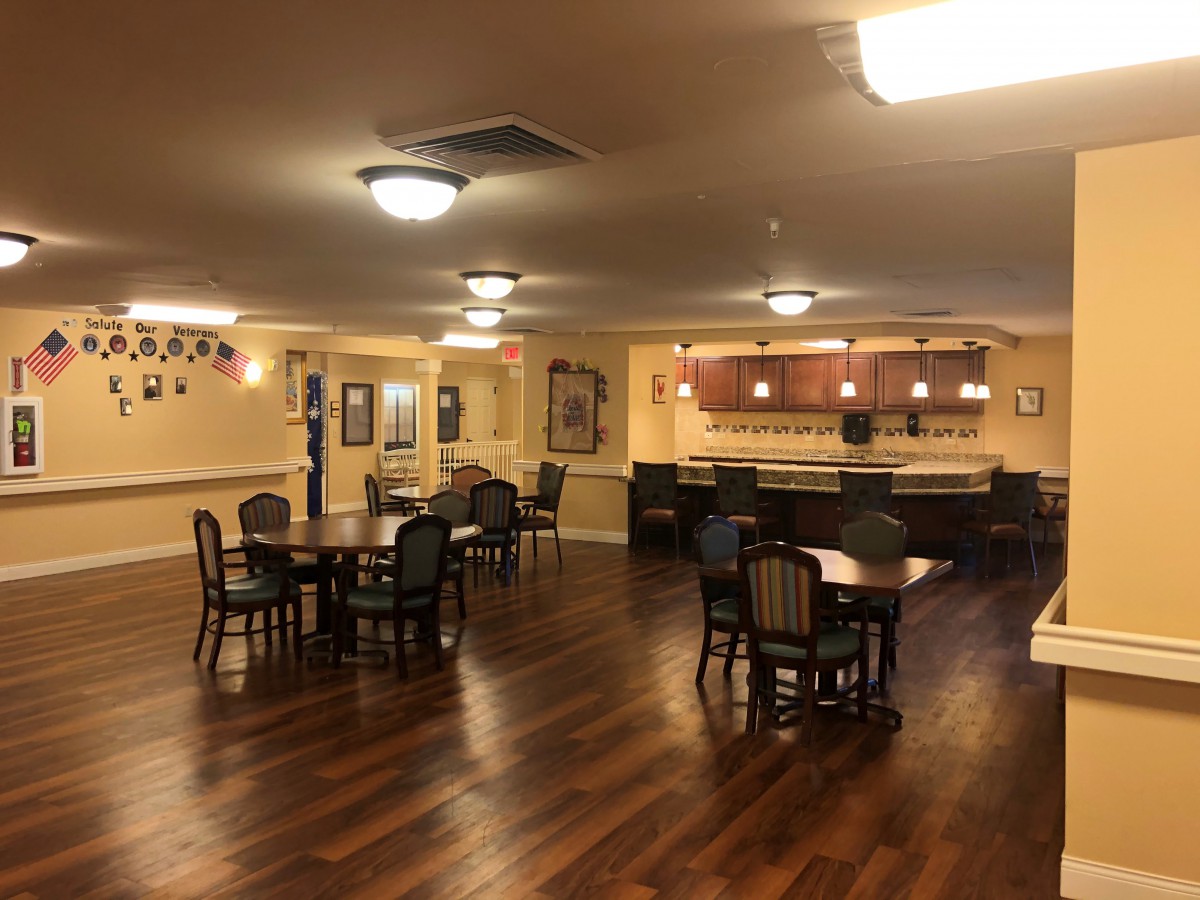 A spacious dining area with several tables and chairs, featuring a bar in the background.