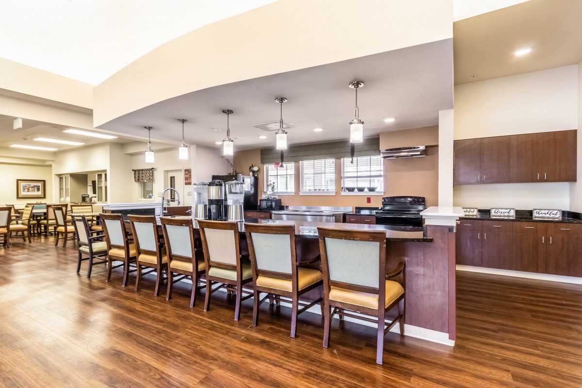 A modern kitchen with a bar area featuring multiple chairs and pendant lighting.