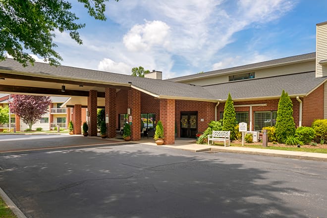 A hotel entrance with a covered driveway and well-maintained landscaping.