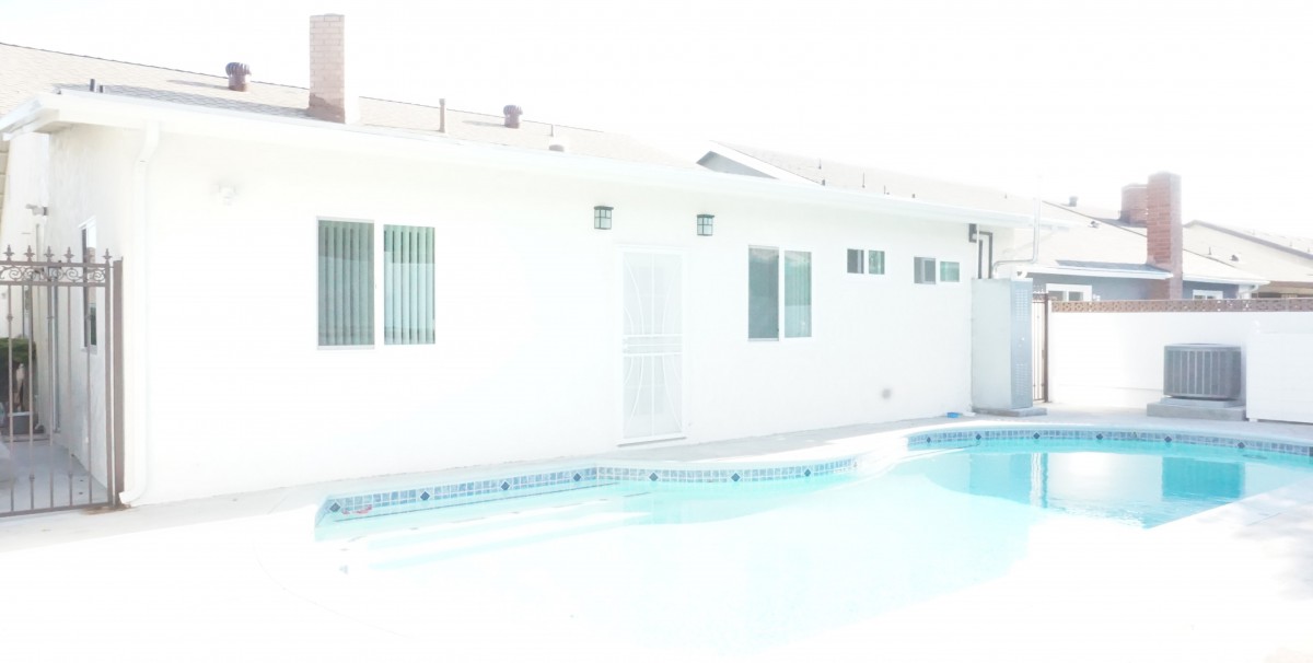 A bright outdoor shot of a house with a swimming pool.