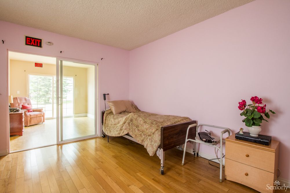 A minimalist bedroom featuring a hospital bed with pink walls and a sliding glass door.