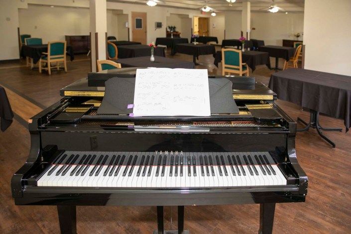 A grand piano with a music sheet in a spacious music room.