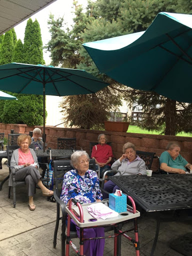 A group of seniors enjoying a sunny day outdoors under umbrellas.