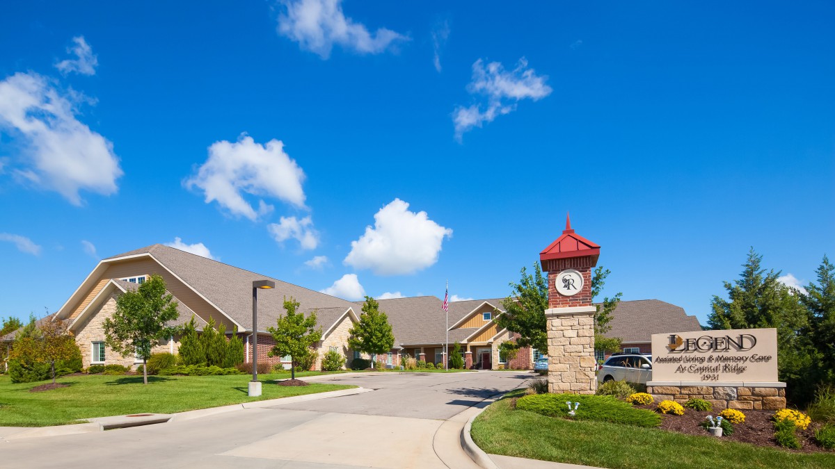 A residential area featuring a clock tower under a clear blue sky with scattered clouds.