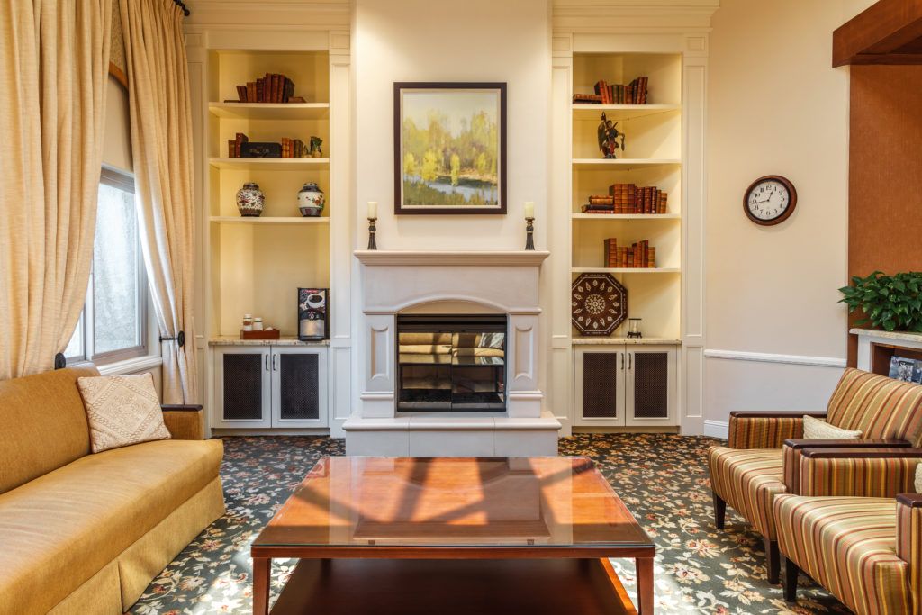 A cozy living room features a central fireplace flanked by built-in bookshelves, with a wooden coffee table and comfortable seating.