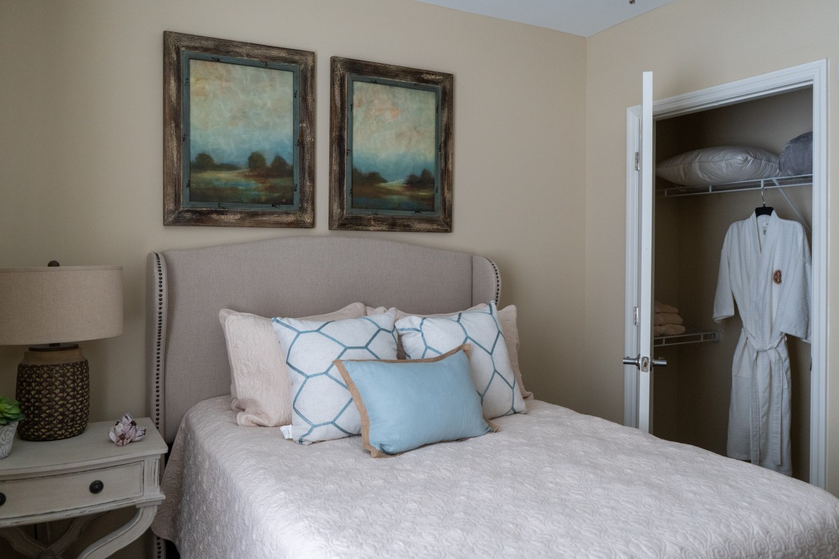 A cozy bedroom with a neatly made bed, accented by decorative pillows and framed artwork above the headboard.