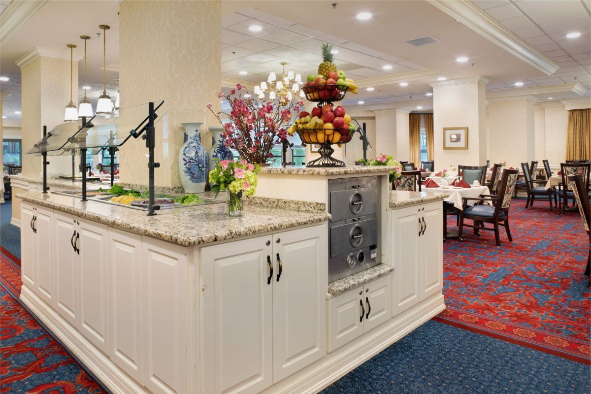 A well-decorated kitchen and dining area featuring a central countertop adorned with flowers and a fruit display.