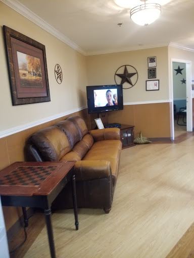 A cozy living room featuring a leather sofa, decorative wall art, and a television setup.