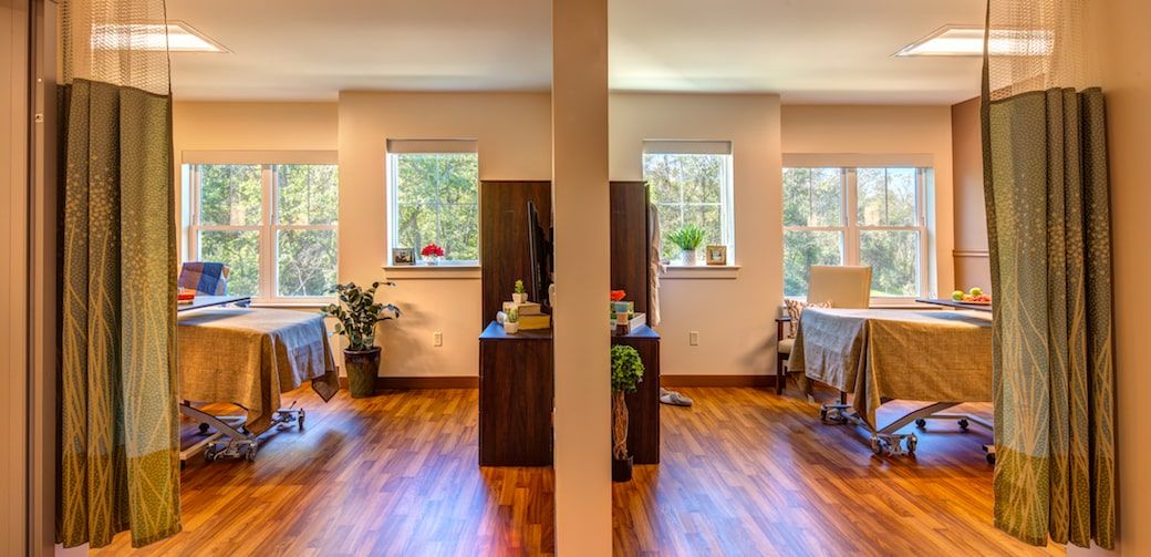 A serene spa massage room with two beds, plants, and calming decor.