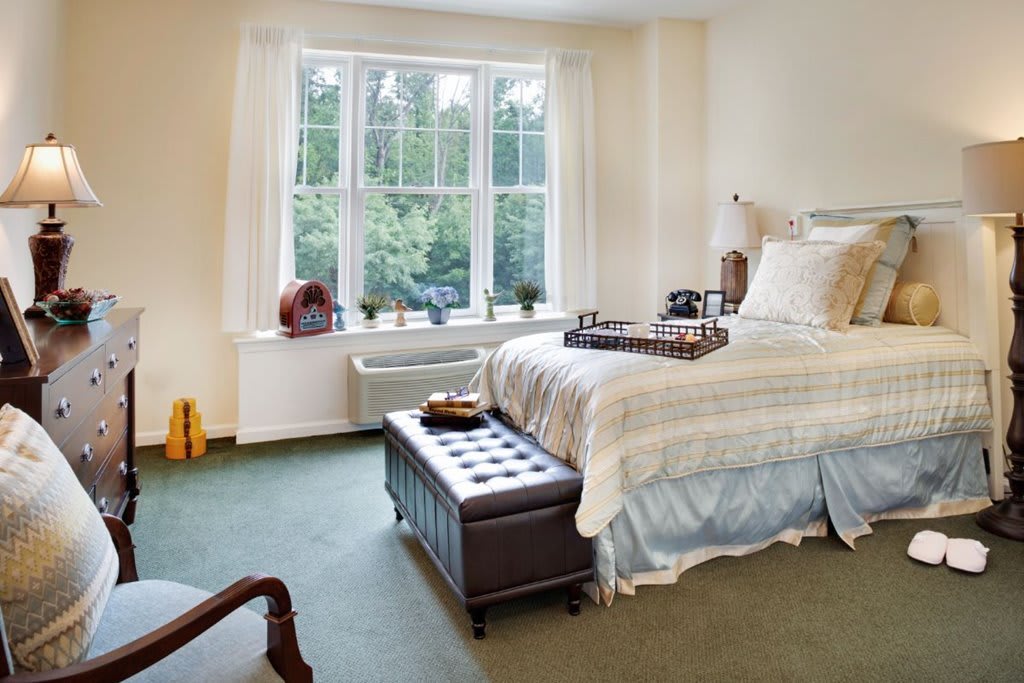 A cozy bedroom with a large window, neatly decorated with comfortable furnishings.