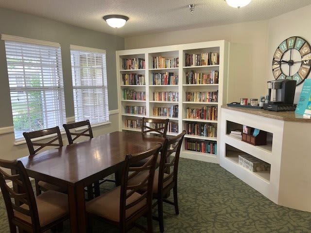 A cozy reading room with bookshelves, a table, and chairs.