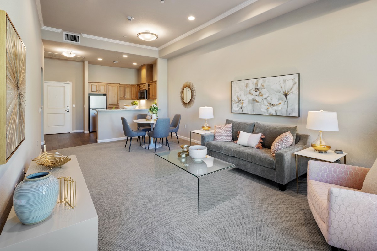 A modern apartment with an open floor plan featuring a stylish living room, dining area, and kitchen.