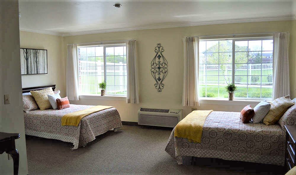 A bright bedroom with two twin beds and large windows allowing natural light.